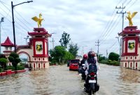 Pengendara motor berhati-hati melewati genangan air di Jalan Trunojoyo, tepatnya di Desa Patean, Kecamatan Batuan, Sumenep. (FOTO: ZAINURRAHMAN / KLIKMADURA).