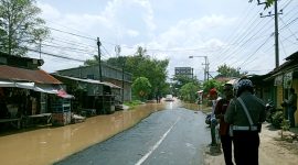 Polisi mengatur lalu lintas di Jalan Imam Bonjol yang mulai dikepung banjir. (SUPRIYANTO / KLIKMADURA)