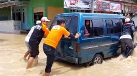 Tim Baznas Tanggap Bencana Sampang mendorong angkutan umum yang terjebak banjir di Kabupaten Sampang. (SUPRIYANTO / KLIKMADURA)