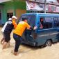Tim Baznas Tanggap Bencana Sampang mendorong angkutan umum yang terjebak banjir di Kabupaten Sampang. (SUPRIYANTO / KLIKMADURA)