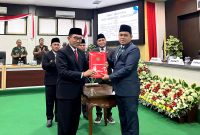 Ketua DPRD Pamekasan Ali Masykur (kanan) menyerahkan dokumen keputusan DPRD terhadap Rekomendasi Perbaikan Penyelenggaraan Pemerintahan Daerah kepada Bupati Pamekasan KH. Kholilurrahman. (MOH. IQBALUL KHAVEI MZ / KLIKMADURA)
