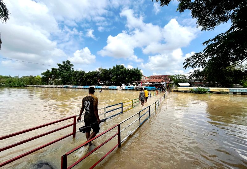 Warga berada di sungai dengan volume air penuh tepatnya di Kelurahan Patemon, Kecamatan Kota Pamekasan. (MOH. IQBALUL KHAVEI MZ / KLIKMADURA)