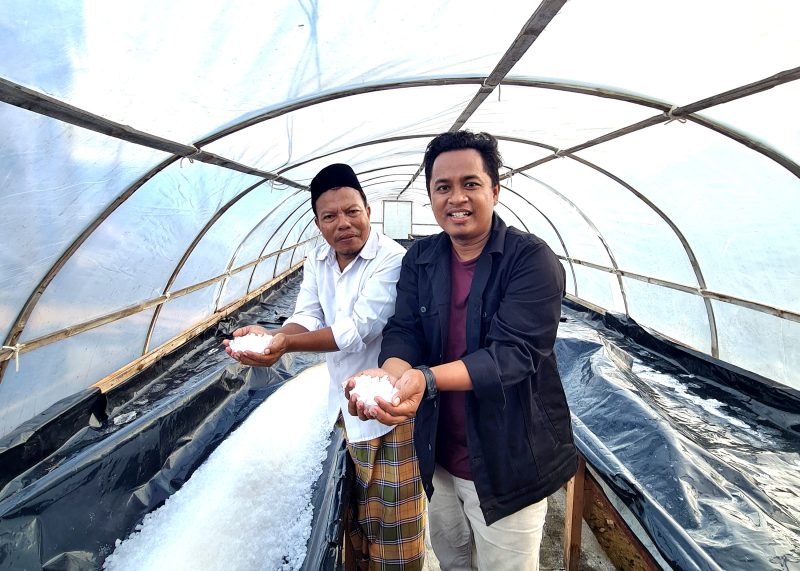 Pemred Klik Madura Prengki Wirananda bersama Pendiri Kedai Reka Cipta Garam Prof. Makhfud Effendi menunjukkan hasil produksi garam dengan kualitas super. (DOK. KLIKMADURA)