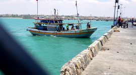 TERIK: Nelayan di Desa Branta Pesisir, Kecamatan Tlanakan, Pamekasan berada di atas kapal saat hendak bersandar. (LAILIYATUN NURIYAH/KLIK MADURA).
