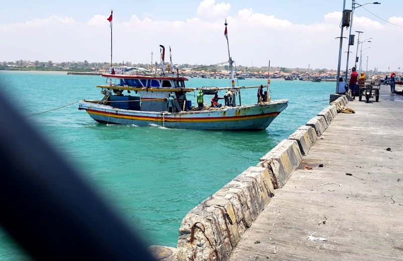 TERIK: Nelayan di Desa Branta Pesisir, Kecamatan Tlanakan, Pamekasan berada di atas kapal saat hendak bersandar. (LAILIYATUN NURIYAH/KLIK MADURA).