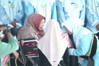 Nyai Hj Halimatus Sa'diyah mengalungkan selempang tanda kelulusan santri. (Al-Amien TV)