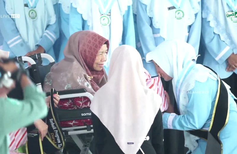 Nyai Hj Halimatus Sa'diyah mengalungkan selempang tanda kelulusan santri. (Al-Amien TV)