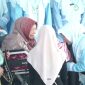 Nyai Hj Halimatus Sa'diyah mengalungkan selempang tanda kelulusan santri. (Al-Amien TV)