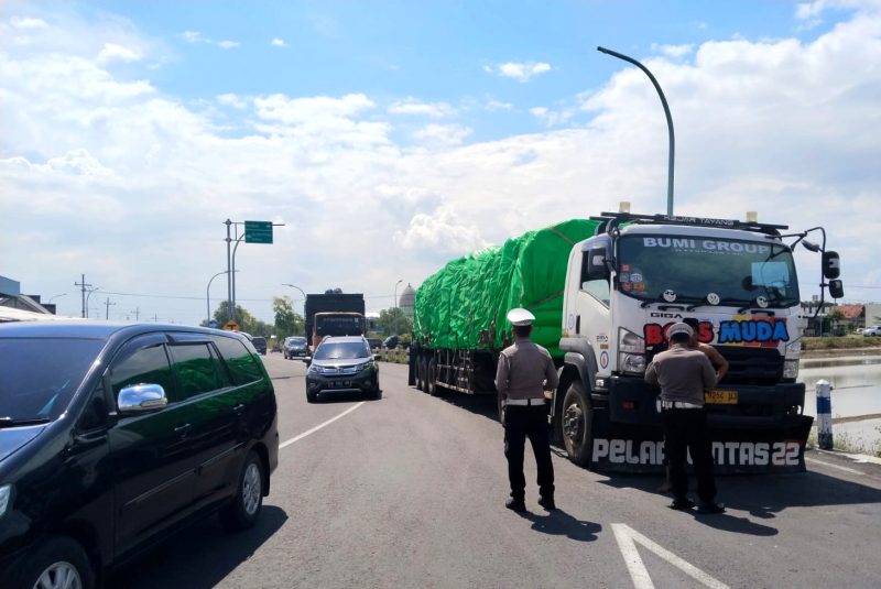 Anggota Satlantas Polres Sampang menyetop truk dengan muatan besar di Jalan Lingkar Selatan (JLS). (IBNU ANSORI / KLIKMADURA)
