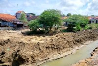 TERIK: Warga berada di sekitar sungai di Jalan Amin Jakfar yang sudah dilakukan pengerukan. (LAILIYATUN NURIYAH/KLIK MADURA).