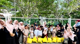 Tim Hijabi Madura foto bersama yatim dan duafa usai penyerahan santunan di area Taman Arek Lancor, Pamekasan. (SARI PURWATI / KLIKMADURA)