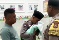 Bhabinkamtibmas Desa Ketapang Barat, Bripka Moh. Jufri mengazani bayi yang ditemukan di area persawahan Desa Ketapang Barat, Kecamatan Ketapang, Sampang. (ISTIMEWA)