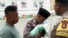 Bhabinkamtibmas Desa Ketapang Barat, Bripka Moh. Jufri mengazani bayi yang ditemukan di area persawahan Desa Ketapang Barat, Kecamatan Ketapang, Sampang. (ISTIMEWA)