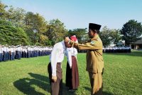 RESMI: Kepala SMPN 1 Pamekasan, Jamil menyematkan kalung tanda pengenal murid baru. (LAILIYATUN NURIYAH/KLIK MADURA).