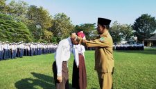 RESMI: Kepala SMPN 1 Pamekasan, Jamil menyematkan kalung tanda pengenal murid baru. (LAILIYATUN NURIYAH/KLIK MADURA).