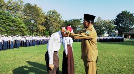 RESMI: Kepala SMPN 1 Pamekasan, Jamil menyematkan kalung tanda pengenal murid baru. (LAILIYATUN NURIYAH/KLIK MADURA).