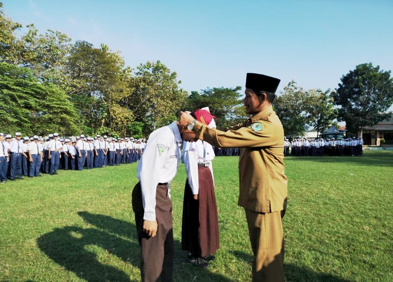 RESMI: Kepala SMPN 1 Pamekasan, Jamil menyematkan kalung tanda pengenal murid baru. (LAILIYATUN NURIYAH/KLIK MADURA).