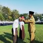 RESMI: Kepala SMPN 1 Pamekasan, Jamil menyematkan kalung tanda pengenal murid baru. (LAILIYATUN NURIYAH/KLIK MADURA).