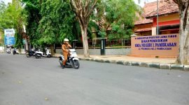 Seorang guru melintas di depan SMAN 1 Pamekasan. (LAILIYATUN NURIYAH / KLIKMADURA)