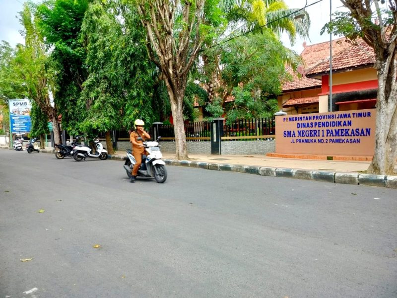 Seorang guru melintas di depan SMAN 1 Pamekasan. (LAILIYATUN NURIYAH / KLIKMADURA)