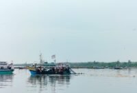SANTAI: Nelayan Branta Pesisir, Kecamatan Tlanakan, Pamekasan menarik jaring di atas kapal. (LAILIYATUN NURIYAH/KLIK MADURA).