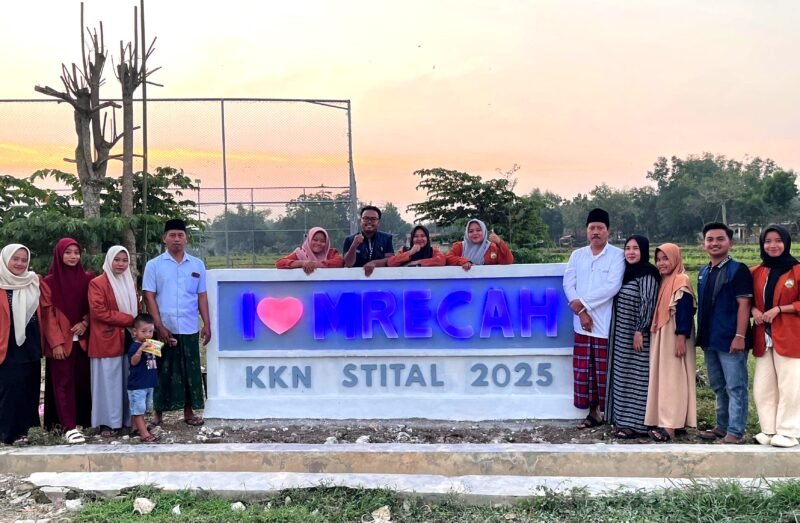 Peserta KKN Kelompok 3, STIT Al-Ibrohimy Bangkalan foto bersama di ikon nama desa yang baru dibangun. (ISTIMEWA)