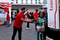 Pjs Pemimpin Cabang Bank Jatim Pamekasan, Yuda Imawan Sutanto menyerahkan nasi kotak kepada warga. (KLIKMADURA)