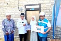 Bupati Pamekasan KH. Kholilurrahman (baju putih) didampingi Assistant Manager Keuangan dan Umum PLN UP3 Madura, Kharisma Nur Khakim menyerahkan bantuan secara simbolis kepada Kamila, guru honorer asal Desa Pamaroh, Kecamatan Kadur, Pamekasan. (MOH. IQBALUL KHAVEI MZ / KLIKMADURA)