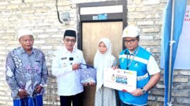 Bupati Pamekasan KH. Kholilurrahman (baju putih) didampingi Assistant Manager Keuangan dan Umum PLN UP3 Madura, Kharisma Nur Khakim menyerahkan bantuan secara simbolis kepada Kamila, guru honorer asal Desa Pamaroh, Kecamatan Kadur, Pamekasan. (MOH. IQBALUL KHAVEI MZ / KLIKMADURA)