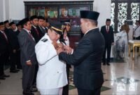 Bupati Sampang H. Slamet Junaidi menyematkan pin tanda jabatan saat pelantikan. (HUMAS PEMKAB SAMPANG FOR KLIKMADURA)