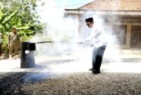 Bupati Pamekasan KH. Kholilurrahman saat membantu warga mengaspal jalan. (KLIKMADURA)