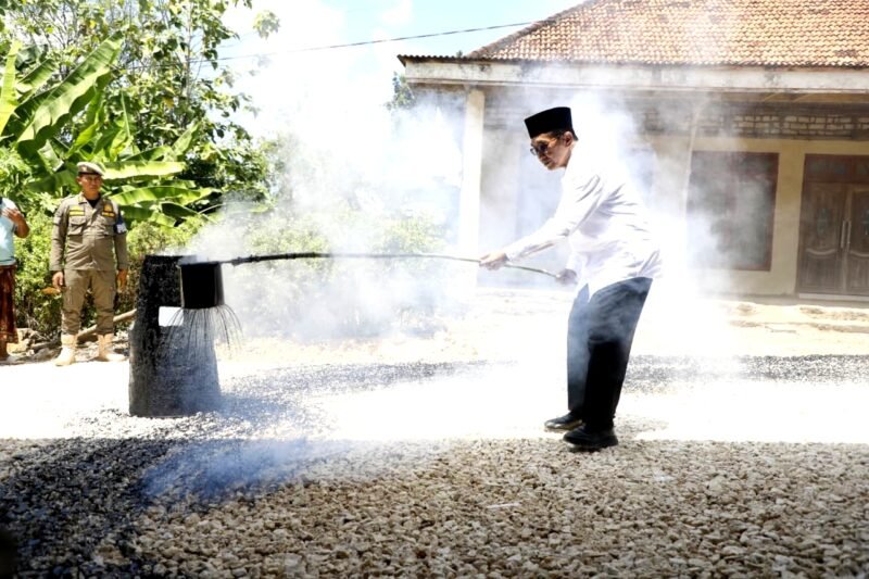 Bupati Pamekasan KH. Kholilurrahman saat membantu warga mengaspal jalan. (KLIKMADURA)