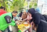 Anggota Hijabi Madura saat memberikan nasi kepada kang ojek pada program pemberian sarapan gratis di sisi timur Taman Arek Lancor, Pamekasan. (KLIKMADURA)