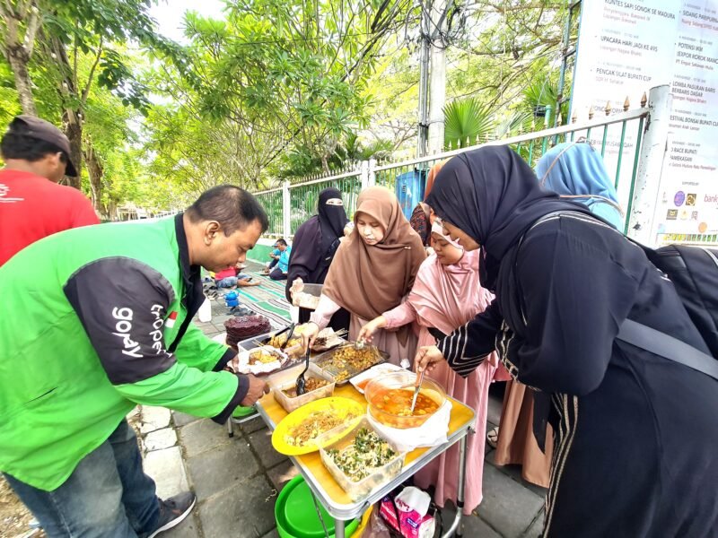 Anggota Hijabi Madura saat memberikan nasi kepada kang ojek pada program pemberian sarapan gratis di sisi timur Taman Arek Lancor, Pamekasan. (KLIKMADURA)