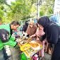 Anggota Hijabi Madura saat memberikan nasi kepada kang ojek pada program pemberian sarapan gratis di sisi timur Taman Arek Lancor, Pamekasan. (KLIKMADURA)