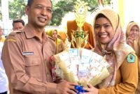 Kepala Dinkes Pamekasan dr. Saifudin menyerahkan hadiah kepada Kepala Puskesmas Pademawu dr. Jeni Novita Anggraini. (DOK. KLIKMADURA)
