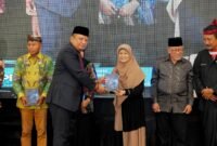 Dirut PT. Royal Madura Media Kita, H. Muhammad Mukid menyerahkan buku kepada psikolog Elly Risman pada kegiatan Gebyar Pendidikan di Ballroom Azana Style Pamekasan. (DOK. SINAR MULYA)