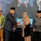 Dirut PT. Royal Madura Media Kita, H. Muhammad Mukid menyerahkan buku kepada psikolog Elly Risman pada kegiatan Gebyar Pendidikan di Ballroom Azana Style Pamekasan. (DOK. SINAR MULYA)
