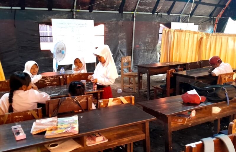 Siswa-siswi SDN Tamberu 2 belajar di bawah tenda milik BPBD Pamekasan lantaran sekolah mereka disegel warga yang mengaku pemilik lahan. (DOK. KLIKMADURA)