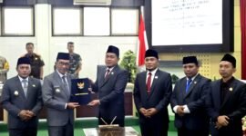 Ketua DPRD Pamekasan, Ali Masykur menyerhakan berkas APBD 2026 kepada Bupati Dr. KH. Kholilurrahaman usai rapat paripurna. (KLIKMADURA)