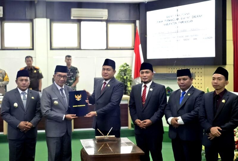 Ketua DPRD Pamekasan, Ali Masykur menyerhakan berkas APBD 2026 kepada Bupati Dr. KH. Kholilurrahaman usai rapat paripurna. (KLIKMADURA)