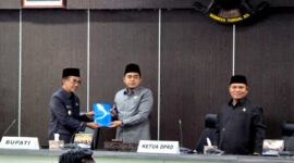 Bupati Pamekasa Dr. KH. Kholilurrahman menyerahkan dokumen jawaban atas PU Fraksi kepada Ketua DPRD Pamekasan, Ali Masykur saat rapat paripurna. (MOH. IQBALUL KHAVEI MZ / KLIKMADURA)