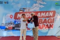Deputi Bisnis PT. Pegadaian Syariah Area Madura, Anwar Hidayat menyerahkan sembako kepada salah satu peserta mudik gratis. (ISTIMEWA)