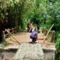 Sejumlah warga berada di jembatan rusak yang dipasangi bambu, tepatnya di Desa Pangorayan, Kecamatan Proppo, Pamekasan. (LAILIYATUN NURIYAH / KLIKMADURA)