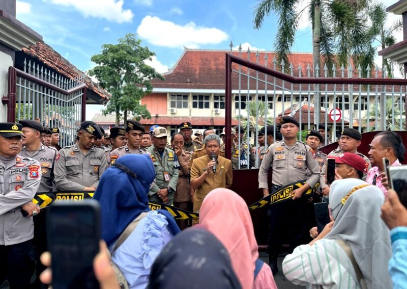 Sekda Pamekasan, Taufikurrachman (pegang mik) saat menemui massa aksi demonstrasi di depan Kantor Bupati Pamekasan. (MOH. IQBALUL KHAVEI MZ / KLIKMADURA)