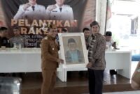 Ketua DKP Pamekasan, Arief Wibisono menyerahkan lukisan kepada Wabup Pamekasan H. Sukriyanto usai pelantikan. (LAILIYATUN NURIYAH / KLIKMADURA)