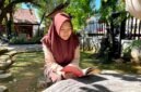 Siswi SMAN 1 Pamekasan Sabrina Yasmin Firyal Siswanto sedang membaca buku di halaman sekolah (LAILIYATUN NURIYAH/KLIK MADURA).