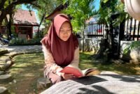 Siswi SMAN 1 Pamekasan Sabrina Yasmin Firyal Siswanto sedang membaca buku di halaman sekolah (LAILIYATUN NURIYAH/KLIK MADURA).