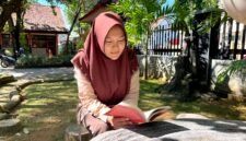 Siswi SMAN 1 Pamekasan Sabrina Yasmin Firyal Siswanto sedang membaca buku di halaman sekolah (LAILIYATUN NURIYAH/KLIK MADURA).