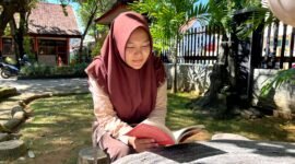 Siswi SMAN 1 Pamekasan Sabrina Yasmin Firyal Siswanto sedang membaca buku di halaman sekolah (LAILIYATUN NURIYAH/KLIK MADURA).